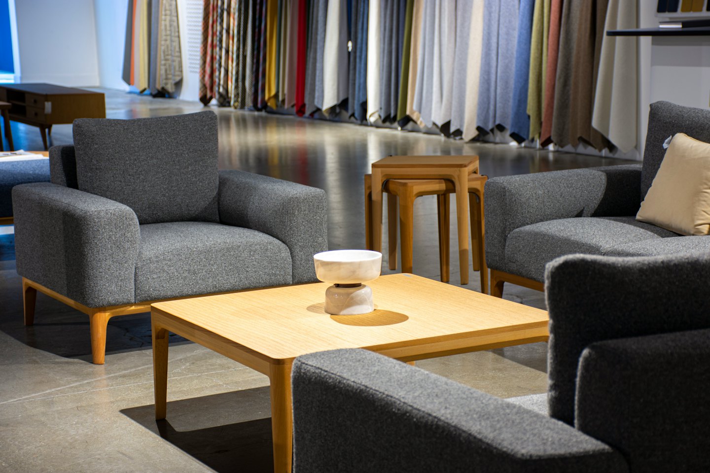 Šiuolaikiniai foteliai ir sofa supa medinį kavos staliuką.
